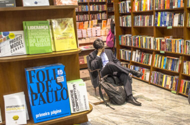 Homem sentado numa livraria lendo